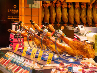 Barcelona, Spain - august 2019: diffrent kinds of jamon on butchery shelves, medium view. Shopping in Barcelona. Jamon background. Selective soft focus. Blurred background