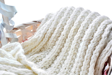 folded long soft warm winter woolen knitted white scarf in basket close up on white background