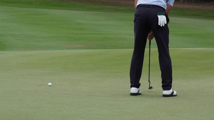 Professional golfer putting golf ball to hole on green golf course on hills in open tournament competition. 