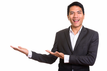 Young happy Asian businessman smiling and showing something