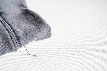 Loose thread on grey shirt on a white background