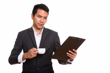 Studio shot of young Asian businessman reading on clipboard whil