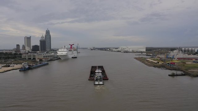Barge and Pushboat inbound to Port of Mobile with the city of Mobile and cruise ship  in the background