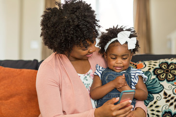 African American mother and daughter playing on the phone.