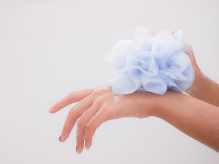 Hands of young woman showering happy and relaxed with puff and foam soap scrub skin