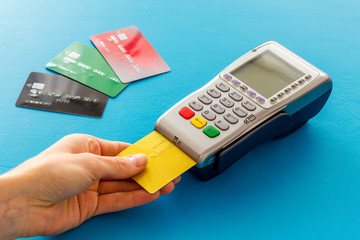 Payments in shops. Hand insert bank card in terminal on blue background