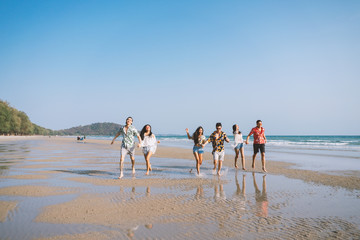 A group of happy friends who play fun on the white sand beach amid the blue sky..