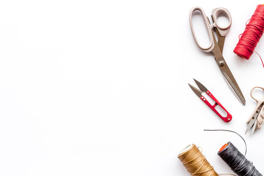 Tailor's work desk. Thread and sciccors on white background top-down copy space