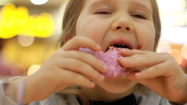 Child eats donut. Closeup baby girl eating doughnut with glase. Delicious, sweet, sweettooth.
