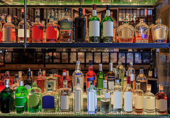 Selection of alcohol bottles on shelves on display at a bar, logos and labels removed. New York United States of America