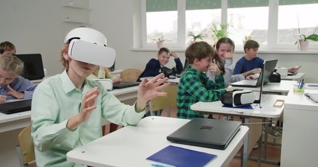 Education at modern school, boy in virtual reality glasses, interacts with a virtual interface and learning in cyberspace, slow motion. - Powered by Adobe