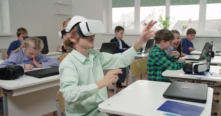 Education at modern school, boy in virtual reality glasses, interacts with a virtual interface and learning in cyberspace. - Powered by Adobe