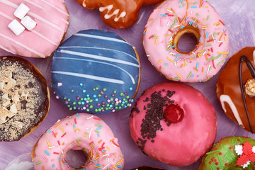 Various colorful donuts on blue background. Top view.