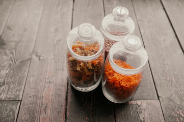 the option of smart food storage in the kitchen, three glass jars for storing raw pasta and groats on a dark wooden table