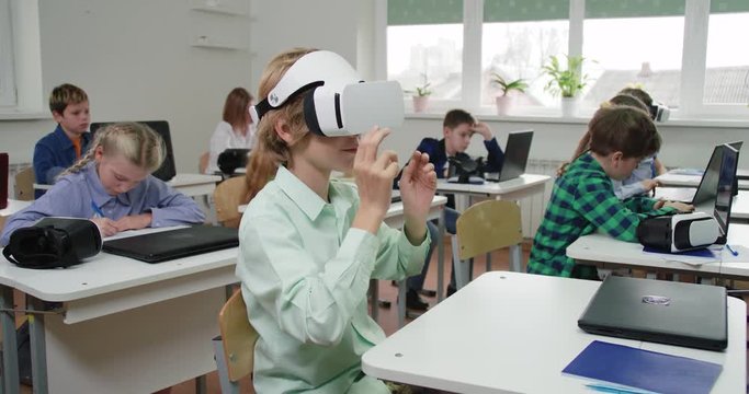 Education at modern school, boy puts on virtual reality glasses, interacts with a virtual interface and learning in cyberspace.