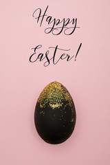 Pink greeting card for Easter with black egg and golden glitter