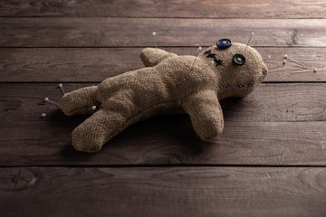 Voodoo doll on a wooden background with dramatic lighting. The concept of witchcraft and black art....