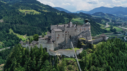 Aerial panoramic view of Hohenwerfen Castle, Austria. Medieval rock fortress in Alpine mountains with spruces. Overlooking the Werfen town in Salzach valley. Summer.