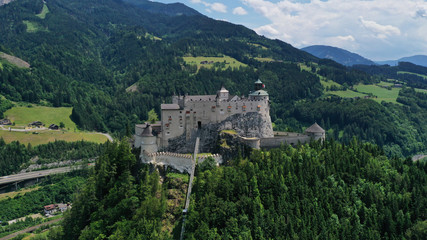 Fototapeta na wymiar Aerial panoramic view of Hohenwerfen Castle, Austria. Medieval rock fortress in Alpine mountains with spruces. Overlooking the Werfen town in Salzach valley. Summer.