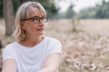 Elderly women caucasian  wear glasses while sitting  think at the public park in the autumn