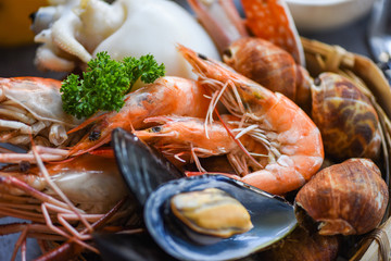 Cooked steamer food served seafood buffet concept - Fresh shrimps prawns squid mussels spotted babylon shellfish crab and seafood sauce lemon on plate background