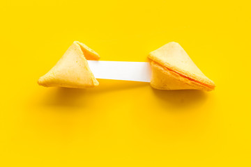 Fortune cookie - broken piece with prediction inside - on yellow background copy space
