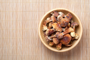 Dried Agaricus blazei mushroom in a wooden bowl on bamboo background. Top view.