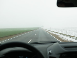 Fototapeta na wymiar Driving in foggy weather. foggy road. bad weather at the wheel, foggy foggy country road. dangerous road. view from the drivers seat