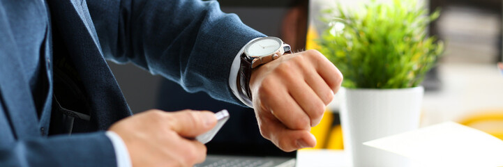 Man in suit and tie check out time at silver wristwatch closeup. Show and point with finger waste...