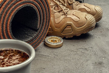 Hiking boots with travel accessories on grunge background