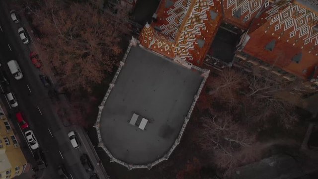 aerial flying forward drone shot above a Univerity Building in Budapest, showing the beautiful architecture of it with colorful tiles on the roof