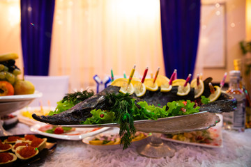 Plate with fish and lemon on banquet table 
