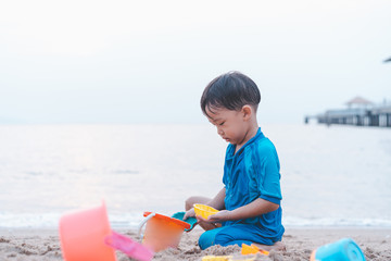 A boy is playing sand and swimming with his brother on the beach.