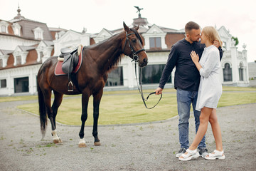 Couple in a summer rainy park. Pair standing with a horse. Girl in a white dress