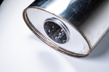 Close-up of the inlet of a new muffler for a car made of stainless steel on a gray background