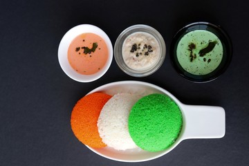 Tiranga Idli or Tricolor Idly cooked in  Indian National Flag colors - saffron or orange, white and green. Served with tiranga chutney. Concept for Indian Independence or Republic day greeting card. 