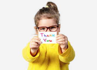 Adorable baby girl is holding a paper with a Thank you note. Silent communication concept. - 315845723