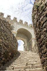 Stone stair goes up to the high floor of ancient medieval castle with knights. Sky with clouds, vertical format, travel concept.