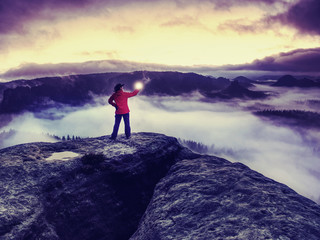 Fototapeta premium Girl on rocky edge above foggy cloud illuminated misty world