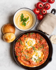 Shakshuka with bell pepper, tomatoes, hummus and rolls. Top view, place for text.