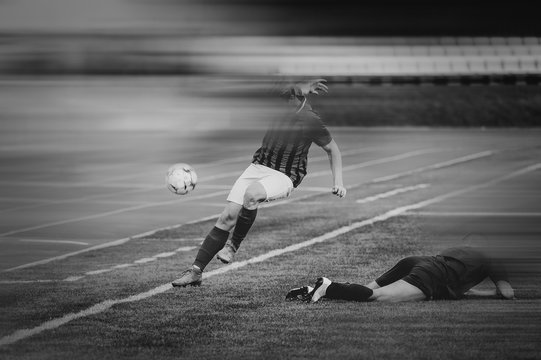 Two men play football. Black and white image. To enhance the effect of the movie, motion blur was added. Copy paste. (Faces blurred in the dark)