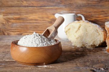 Fototapeta na wymiar Bowl with flour and scoop on wooden table