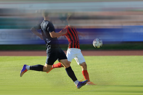 Two men play football. Color image. To enhance the effect of the movie, motion blur was added. Copy paste. (Faces blurred)