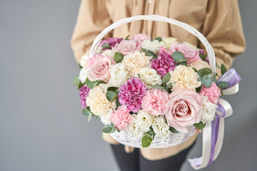 Flowers delivery. Flower arrangement in Wicker basket. Beautiful bouquet of mixed flowers in woman...
