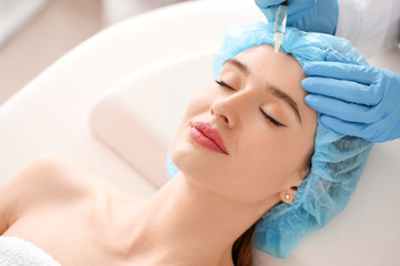 Young woman receiving filler injection in beauty salon