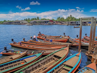 view of many long-tail boats floating in port with cloudy sky background, Ranong Province, south of Thailand.