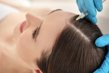 Young woman with hair loss problem receiving injection in beauty salon, closeup