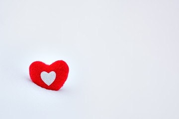 Red woolen heart in a snowdrift in winter close up, with place for text. Winter snow bright background. Holiday landscape, snowdrifts and red heart in the frost.