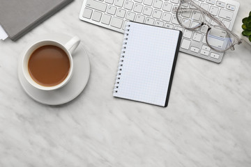 Notebook with cup of coffee and computer keyboard on table