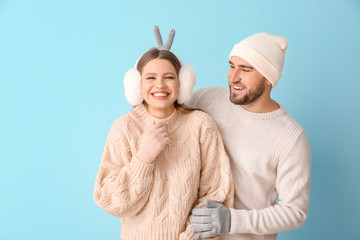 Portrait of happy couple in winter clothes on color background